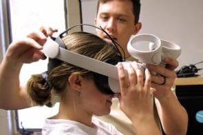 Dr. Jared Branch helps a student adjust a virtual reality headset in the cognitive science lab