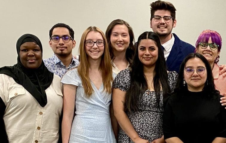 8 senior Avila social work students standing in front of a wall