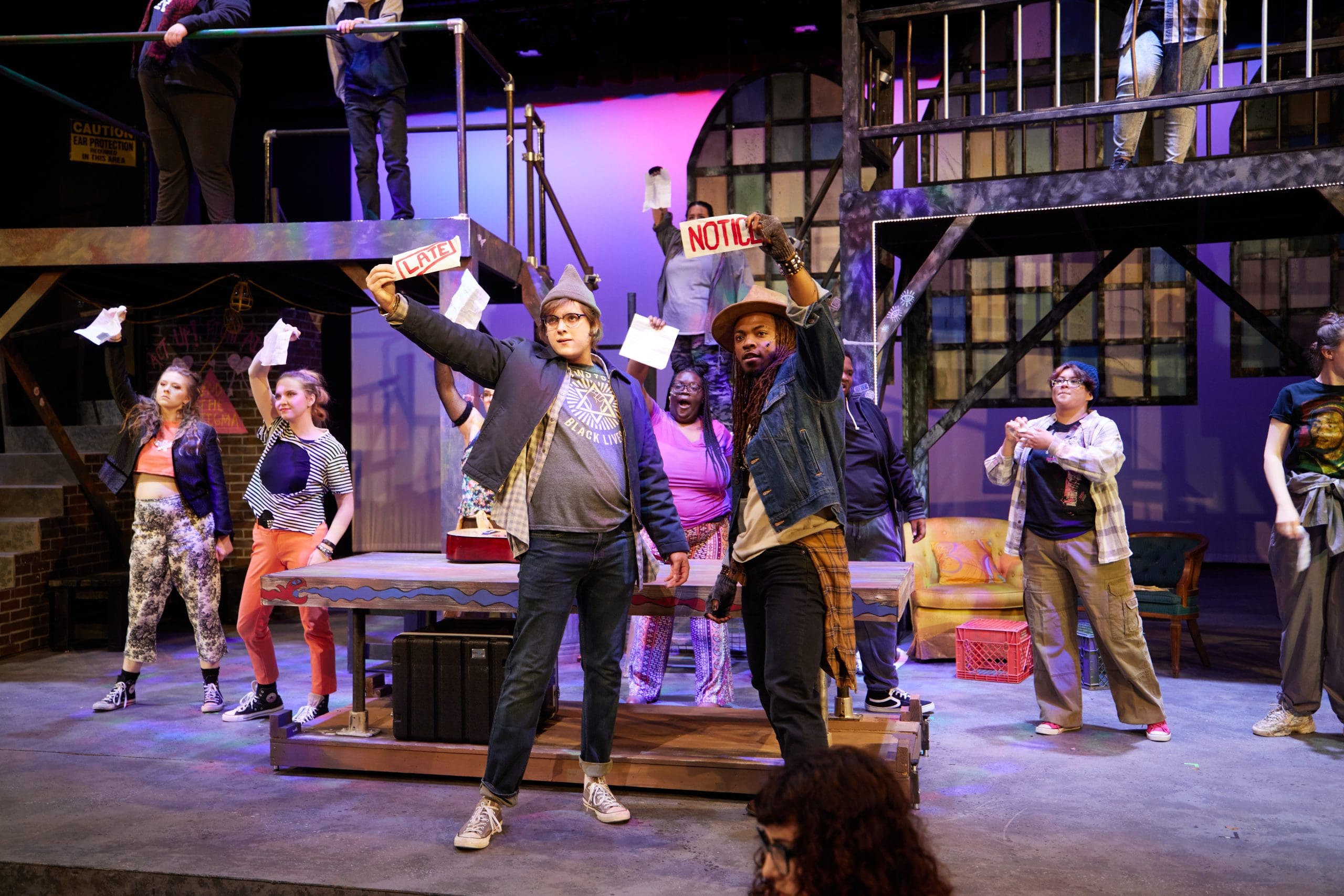 A group of actors on stage holding signs