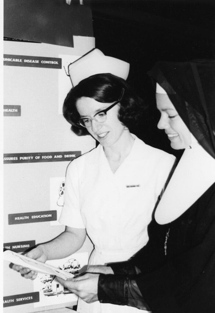 A nurse and a nun look at a document.