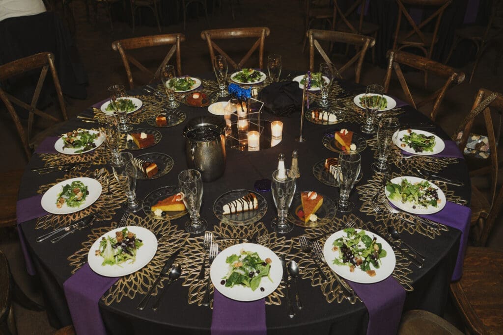 A man and two women dressed in western-inspired and formal attire smile together for a photo at the Avila University 50th Steer Dinner gala event.