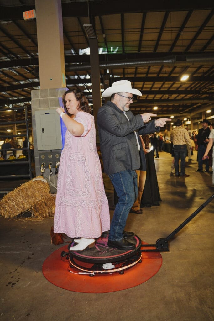 A couple dressed in formal western attire share a dance on the event floor at the Avila University 50th Steer Dinner, surrounded by other guests and festive décor including hay bales.