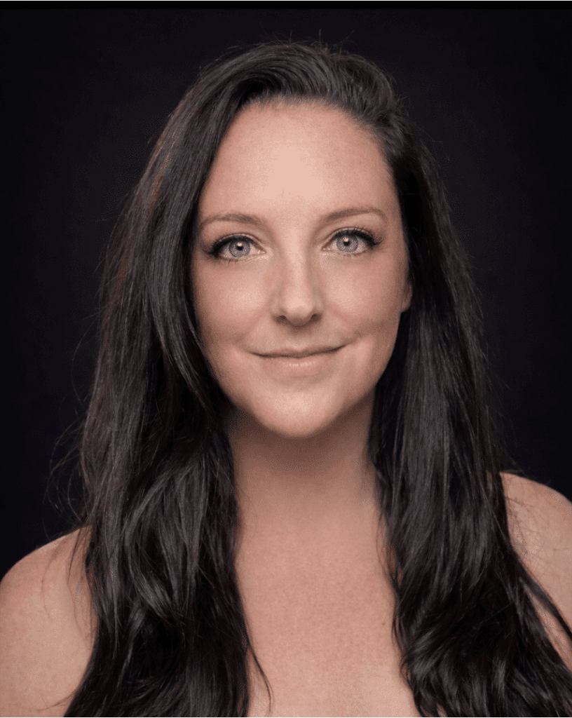 Photograph of a person with long dark hair against a black background. The face is blurred, focusing attention on hair texture and shoulder area.