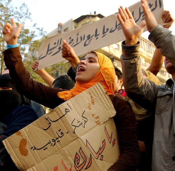 Crowd of protesters holding signs with Arabic text during a public demonstration in Egypt